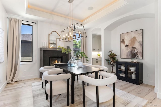 852 Pontiac St, Denver, CO 80220 - dining area with a tray ceiling, light wood finished floors, a glass covered fireplace, ornamental molding, and a chandelier