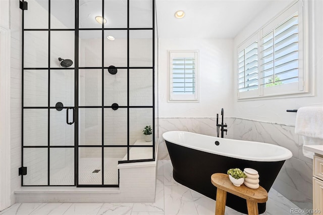 852 Pontiac St, Denver, CO 80220 - full bath featuring marble look tiles, tile walls, a shower stall, a soaking tub, and wainscoting