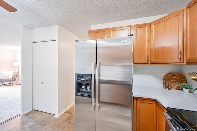 kitchen with brown cabinetry, decorative backsplash, light countertops, and stainless steel fridge