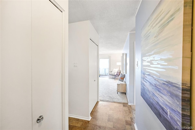 hallway featuring light carpet and a textured ceiling