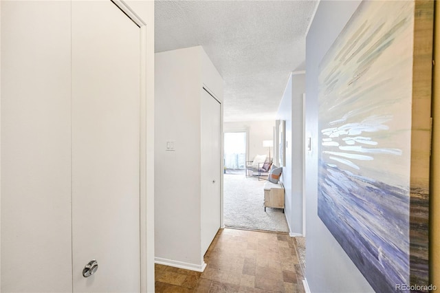corridor featuring baseboards and a textured ceiling