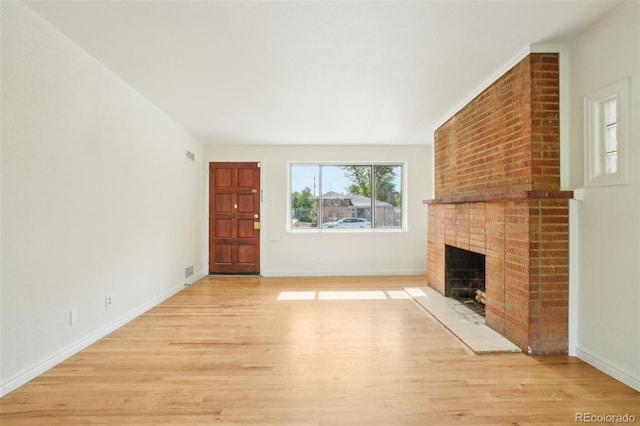 6155 Carr St, Arvada, CO 80004 - unfurnished living room featuring light wood-style floors, a brick fireplace, and baseboards