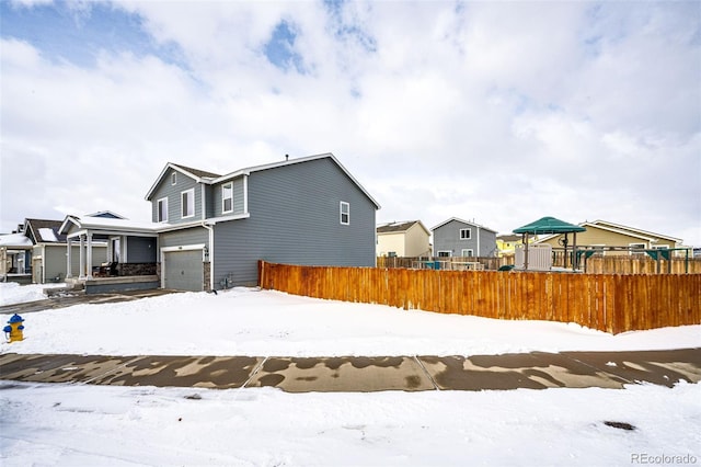 snow covered rear of property featuring a garage