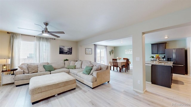 living room with ceiling fan, sink, and light hardwood / wood-style floors