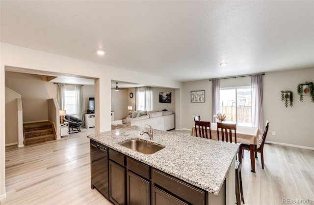 kitchen with a kitchen island with sink, sink, black dishwasher, plenty of natural light, and dark brown cabinetry