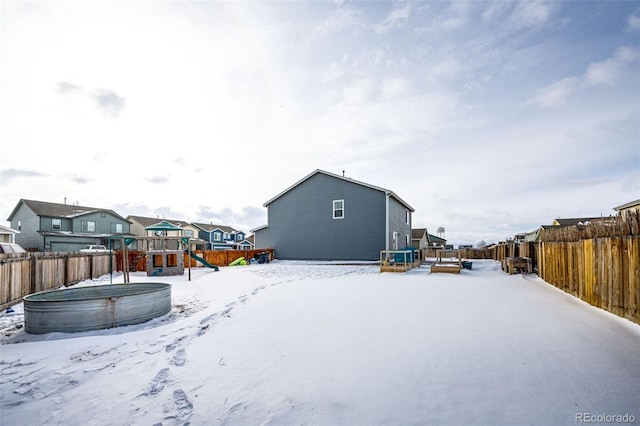 snowy yard featuring a deck and a playground