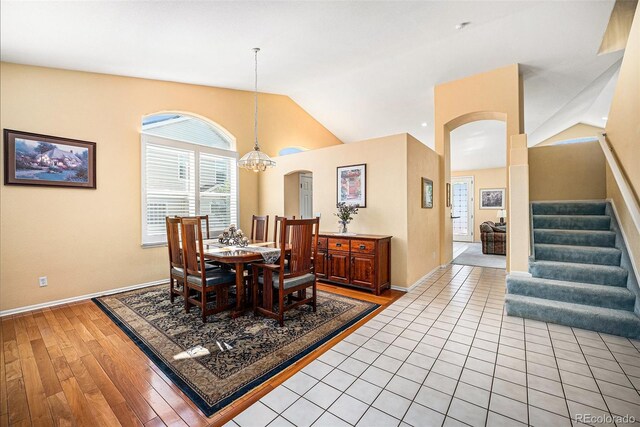 1010 Home Farm Cir, Denver, CO 80234 - dining area featuring arched walkways, vaulted ceiling, light wood-style flooring, stairs, and a chandelier