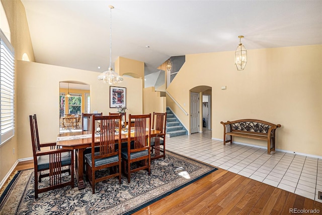 1010 Home Farm Cir, Denver, CO 80234 - dining area with arched walkways, a chandelier, wood finished floors, high vaulted ceiling, and stairs