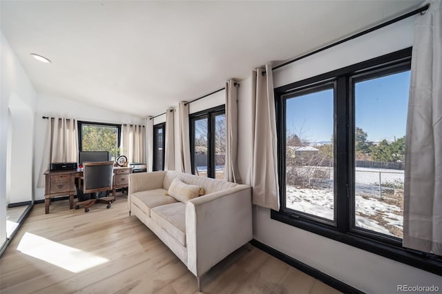 living room featuring light wood-type flooring, plenty of natural light, and lofted ceiling