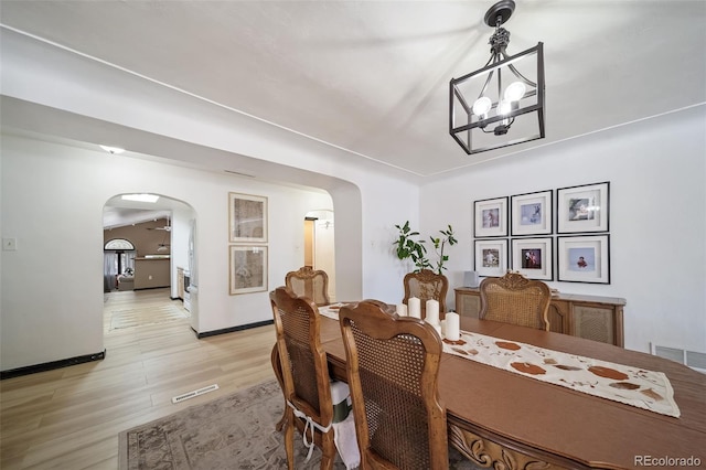 dining space with light hardwood / wood-style flooring and an inviting chandelier