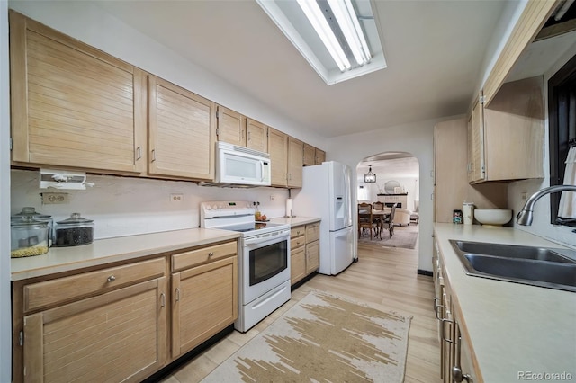 kitchen with sink, light hardwood / wood-style floors, white appliances, and light brown cabinets