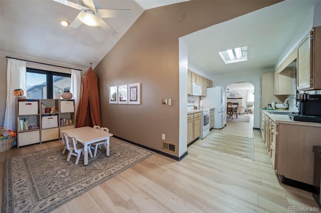 kitchen with white appliances, ceiling fan, sink, light hardwood / wood-style floors, and lofted ceiling