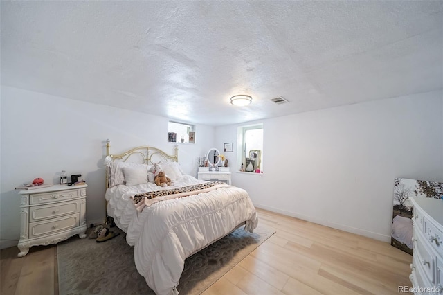 bedroom featuring a textured ceiling and light hardwood / wood-style flooring