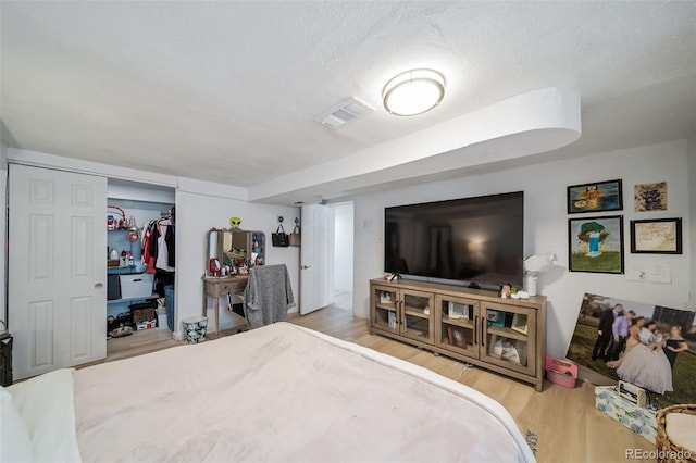 bedroom with a textured ceiling, light hardwood / wood-style flooring, and a closet