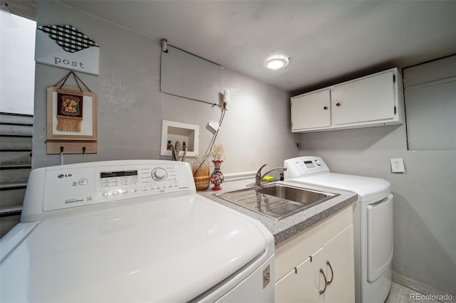 clothes washing area featuring washer and clothes dryer, cabinets, and sink