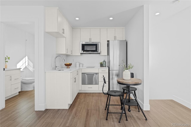 kitchen featuring white cabinetry, stainless steel appliances, light hardwood / wood-style floors, and sink