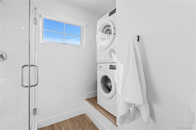 laundry room featuring hardwood / wood-style flooring and stacked washing maching and dryer