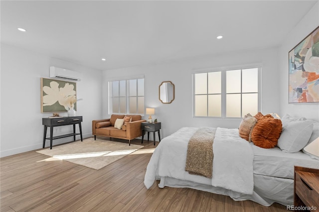 bedroom with a wall mounted air conditioner and light hardwood / wood-style floors