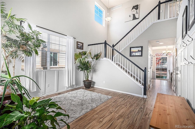 foyer entrance with hardwood / wood-style flooring, a high ceiling, and a chandelier