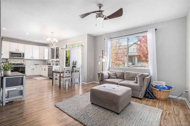 living room featuring light wood-type flooring and ceiling fan with notable chandelier