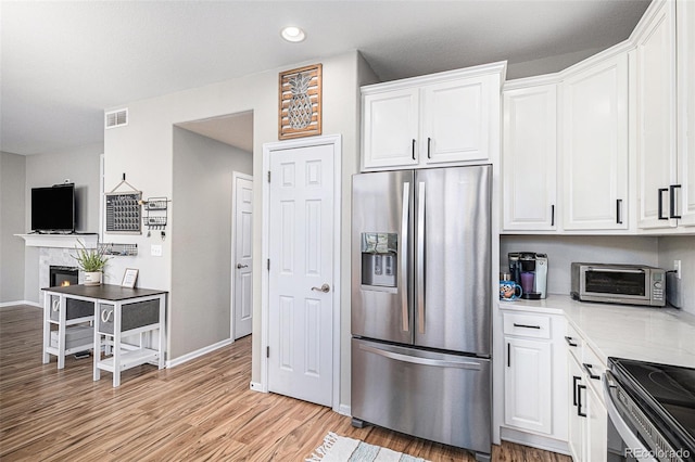 kitchen with white cabinetry, stainless steel refrigerator with ice dispenser, and light hardwood / wood-style flooring