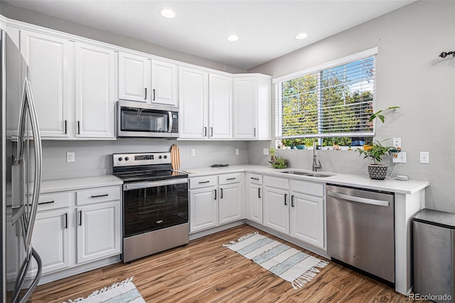 kitchen with sink, white cabinets, stainless steel appliances, and light hardwood / wood-style floors