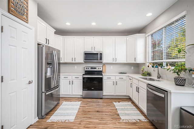 kitchen with light hardwood / wood-style flooring, white cabinetry, stainless steel appliances, and sink