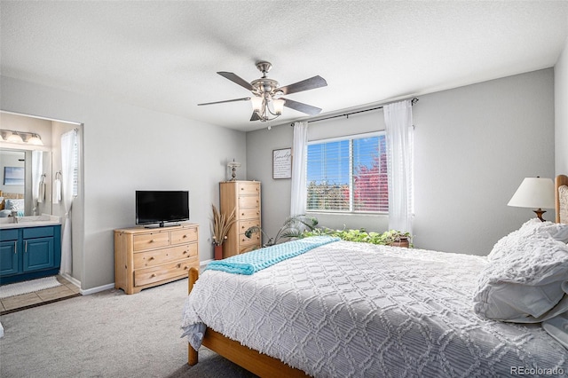 bedroom with ensuite bathroom, sink, a textured ceiling, ceiling fan, and light carpet