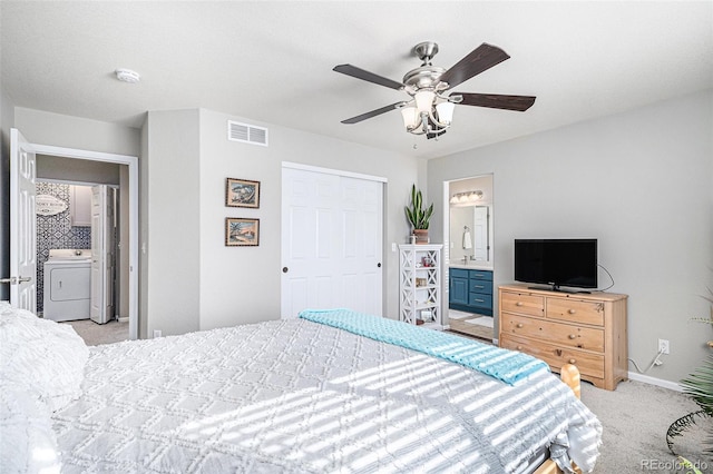 bedroom with light carpet, washer / clothes dryer, ceiling fan, a closet, and ensuite bath