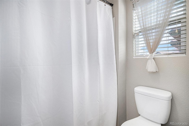 bathroom with toilet and a shower with shower curtain