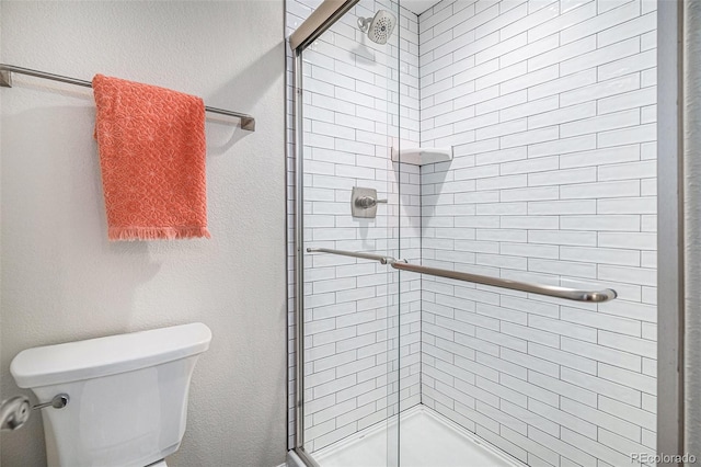 bathroom with a shower with door and toilet