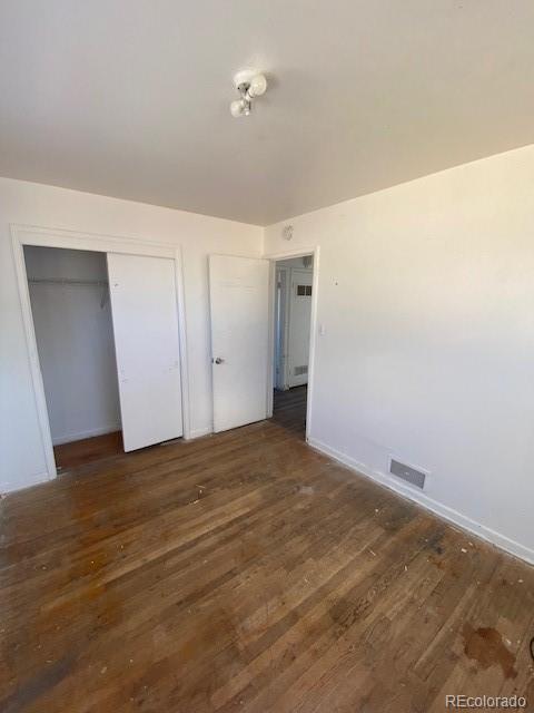 unfurnished bedroom with dark hardwood / wood-style flooring and a closet