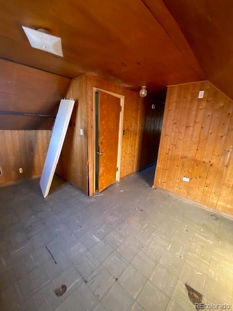 bonus room featuring wooden walls and vaulted ceiling