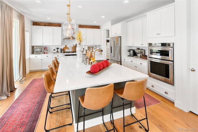 2855 Pawnee Creek Dr, Loveland, CO 80538 - kitchen featuring stainless steel appliances, light wood-style floors, decorative backsplash, light countertops, and recessed lighting