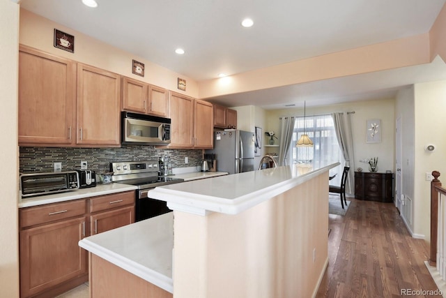 kitchen featuring appliances with stainless steel finishes, light countertops, decorative backsplash, and an island with sink