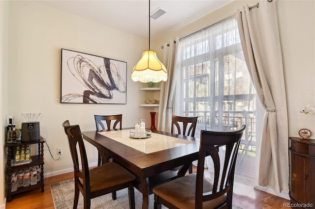 dining space with baseboards, visible vents, and wood finished floors