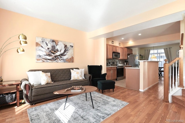 living room featuring light wood finished floors and stairway