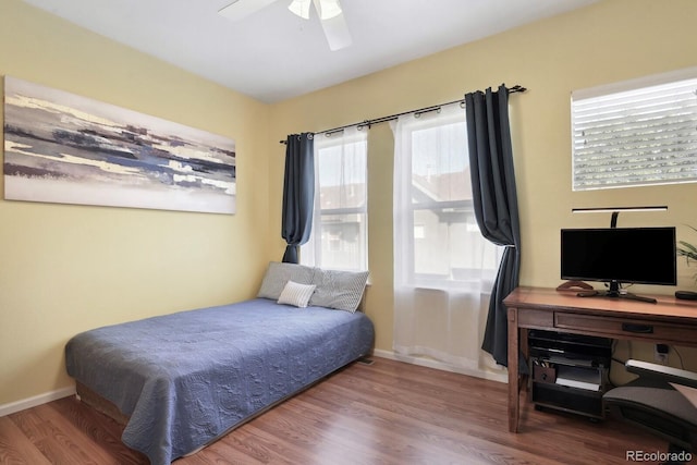 bedroom featuring wood finished floors, a ceiling fan, and baseboards