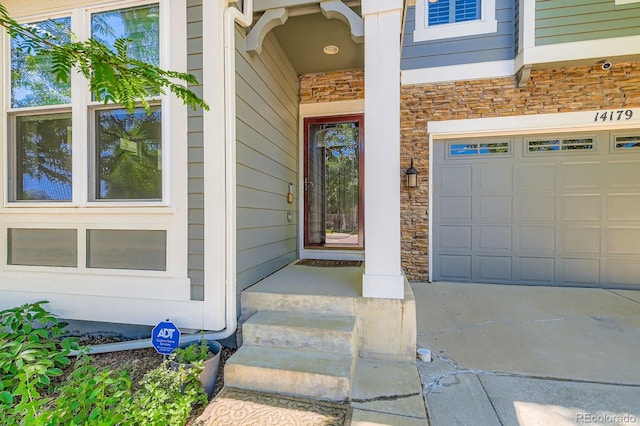 14179 Madison St, Thornton, CO 80602 - doorway to property with stone siding, a garage, and concrete driveway