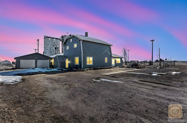 property exterior at dusk featuring a garage and an outdoor structure