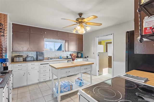 48 Elm St, Arriba, CO 80804 - kitchen with stainless steel refrigerator, white cabinetry, sink, light tile patterned floors, and dark brown cabinets