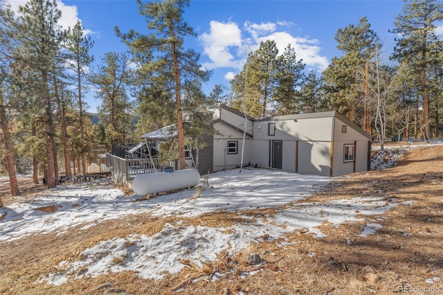 snow covered house featuring a wooden deck