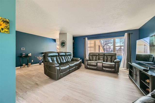 living room featuring a textured ceiling, baseboards, and wood finished floors