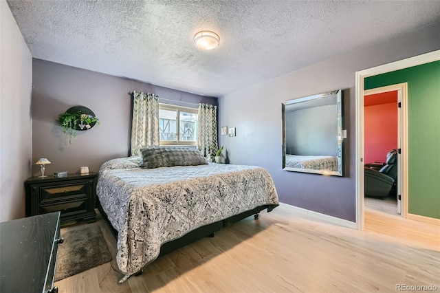 bedroom with a textured ceiling, baseboards, and wood finished floors