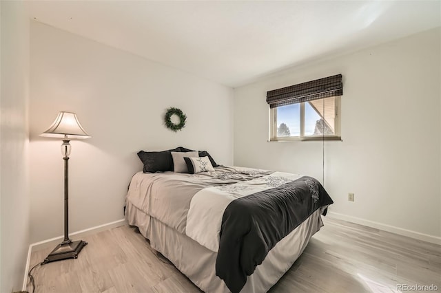 bedroom featuring baseboards and light wood finished floors