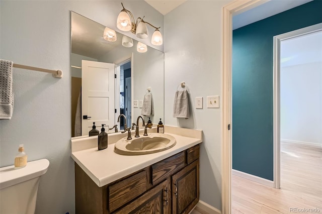 bathroom with vanity, wood finished floors, toilet, and baseboards