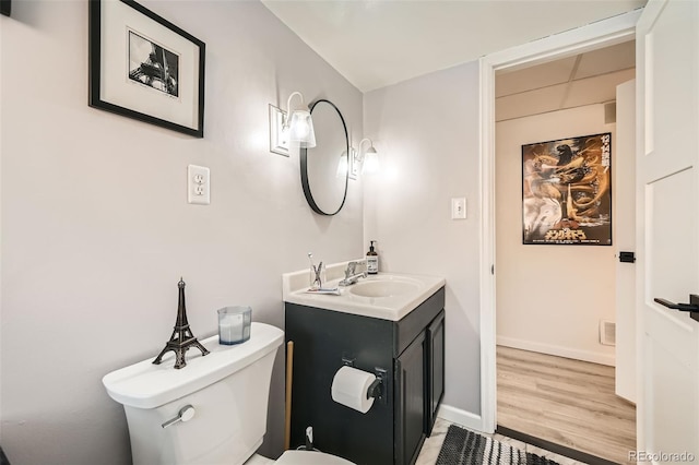 bathroom featuring baseboards, vanity, toilet, and wood finished floors