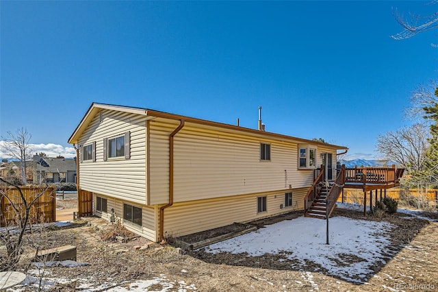 snow covered property with stairway and a wooden deck