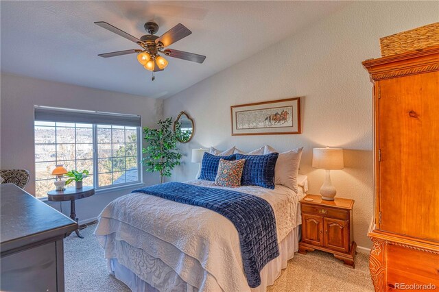 bedroom with a textured wall, vaulted ceiling, a ceiling fan, and light colored carpet