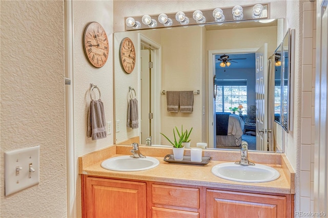 ensuite bathroom featuring double vanity, ensuite bath, a sink, and a textured wall